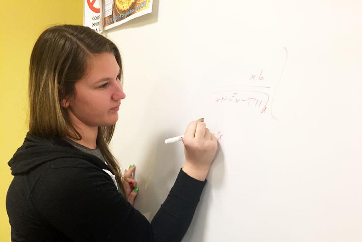 Tutor solving equation on white board